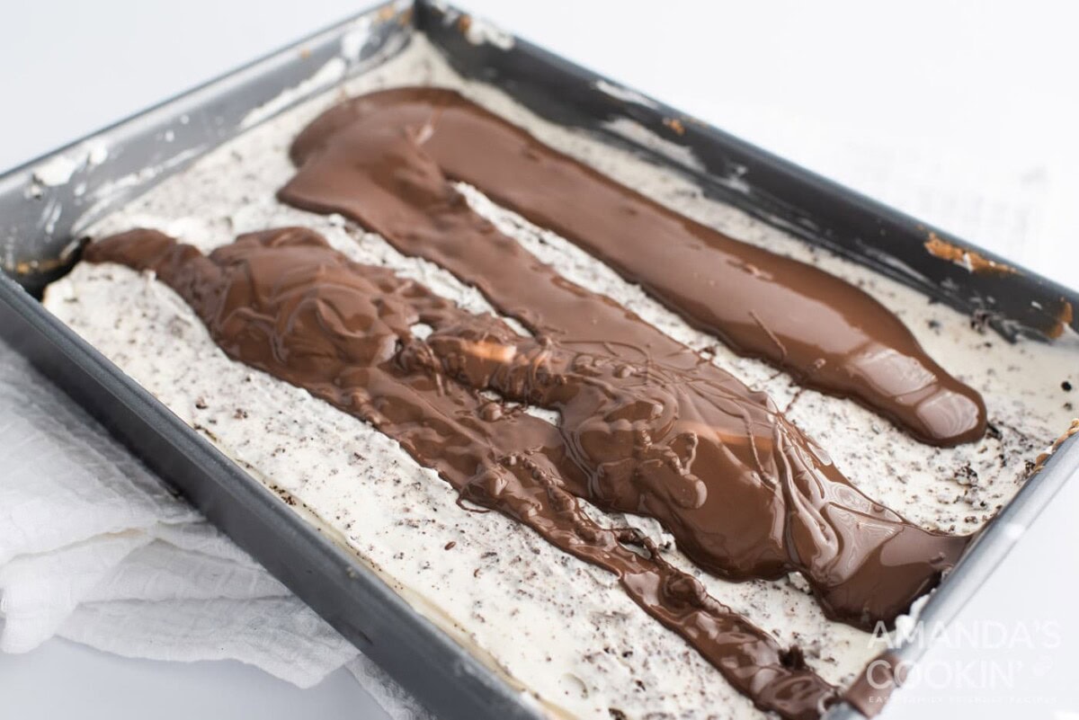 chocolate ganache topping on oreo cheesecake in a pan