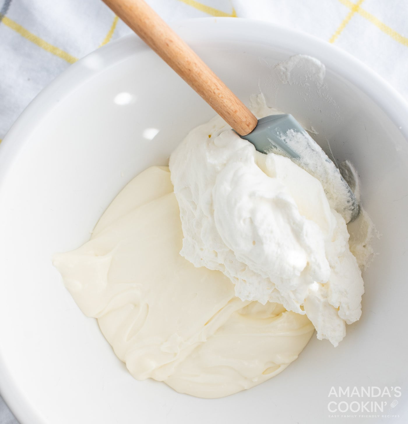 spatula folding in whipped cream into cream cheese mixture