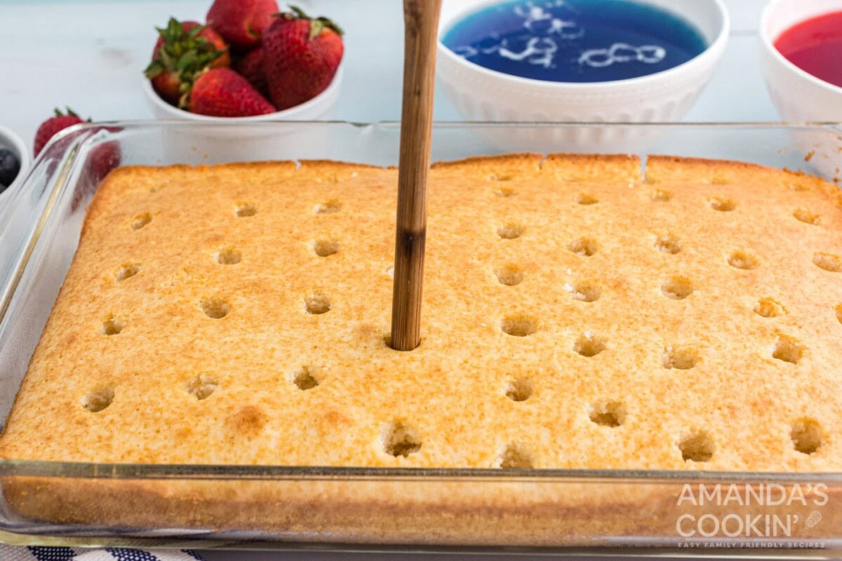poking holes in a cake with a wooden spoon handle