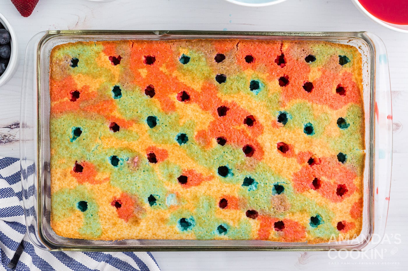 blue and red jello over the top of a white cake mix with holes