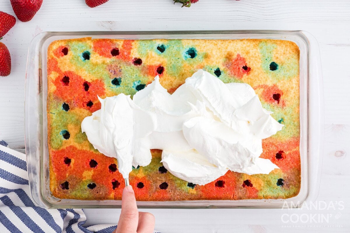 spreading cool whip over the top of poke cake