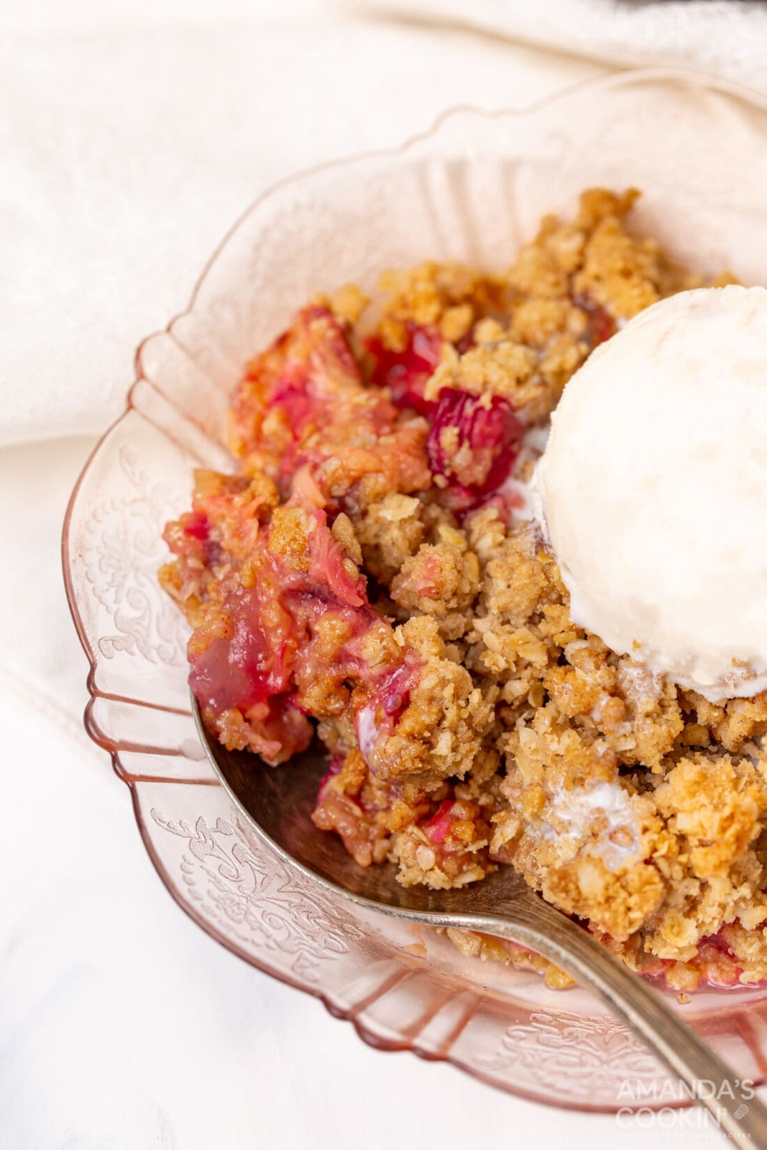 rhubarb crisp in a pink bowl with ice cream