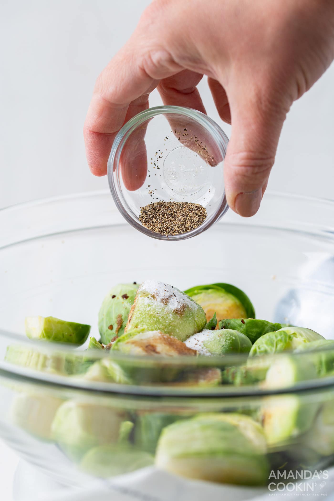 pouring pepper over brussels sprouts
