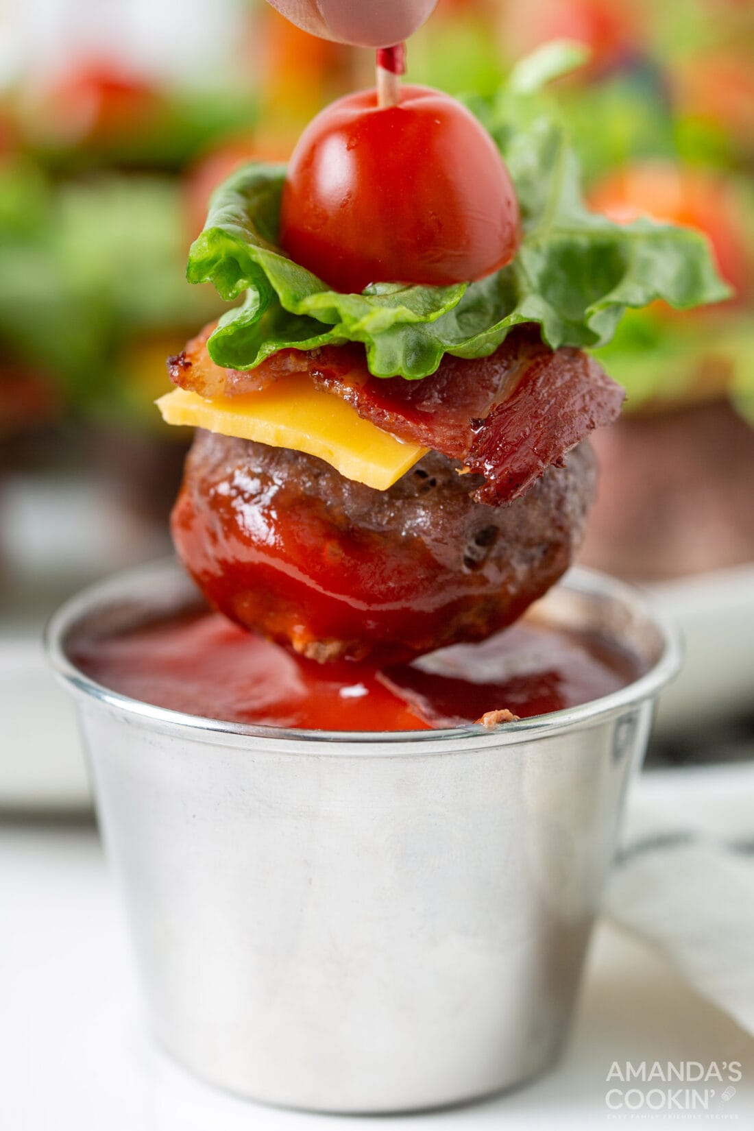 dipping a Bacon Cheeseburger Meatball appetizer in ketchup