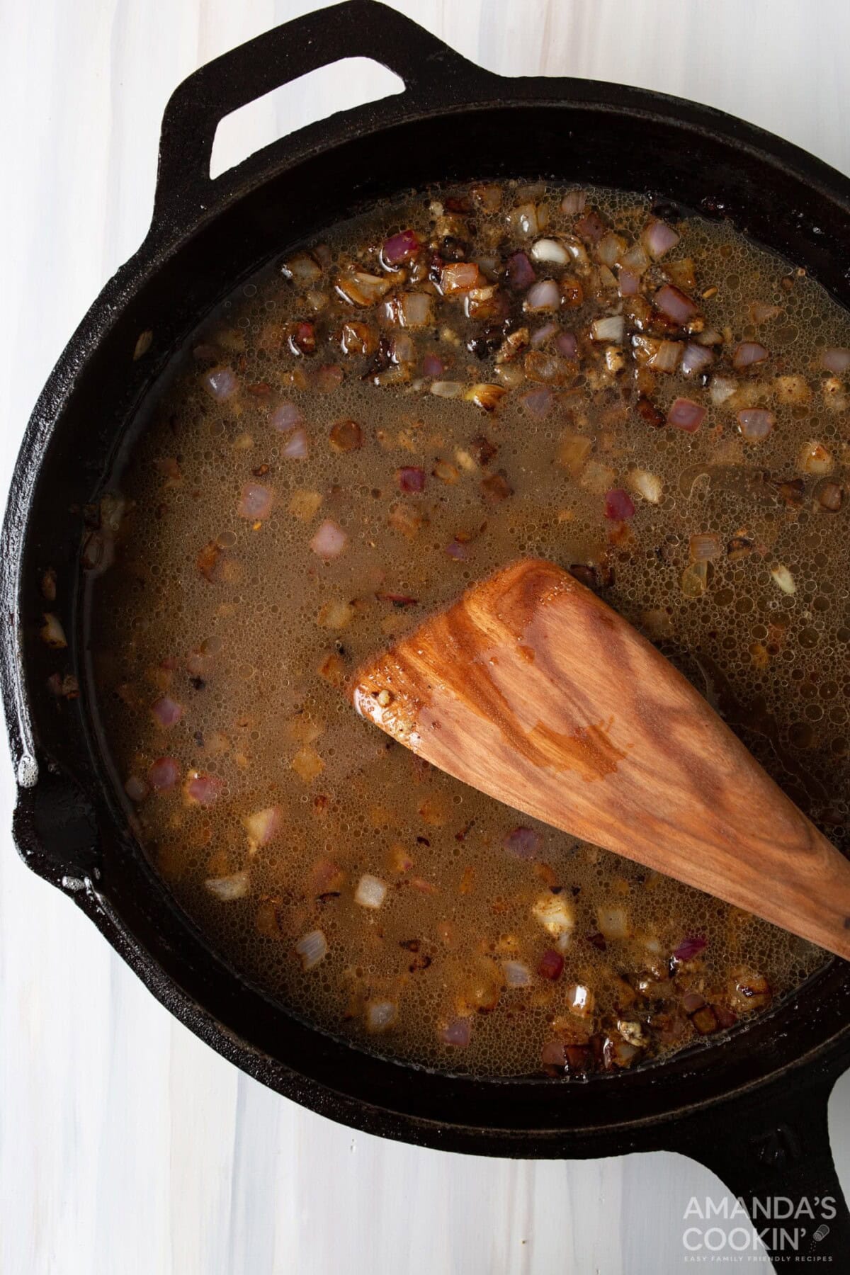 wood spatula stirring in garlic on a skillet