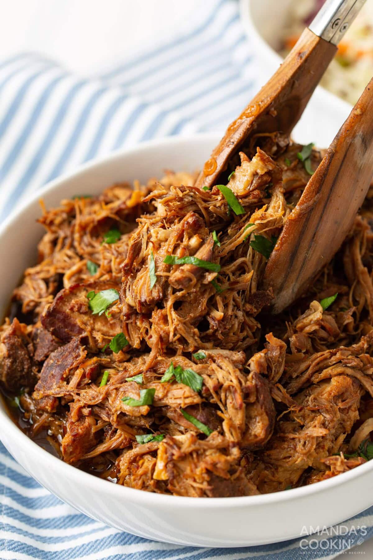 tongs in a bowl of Instant Pot Pulled Pork