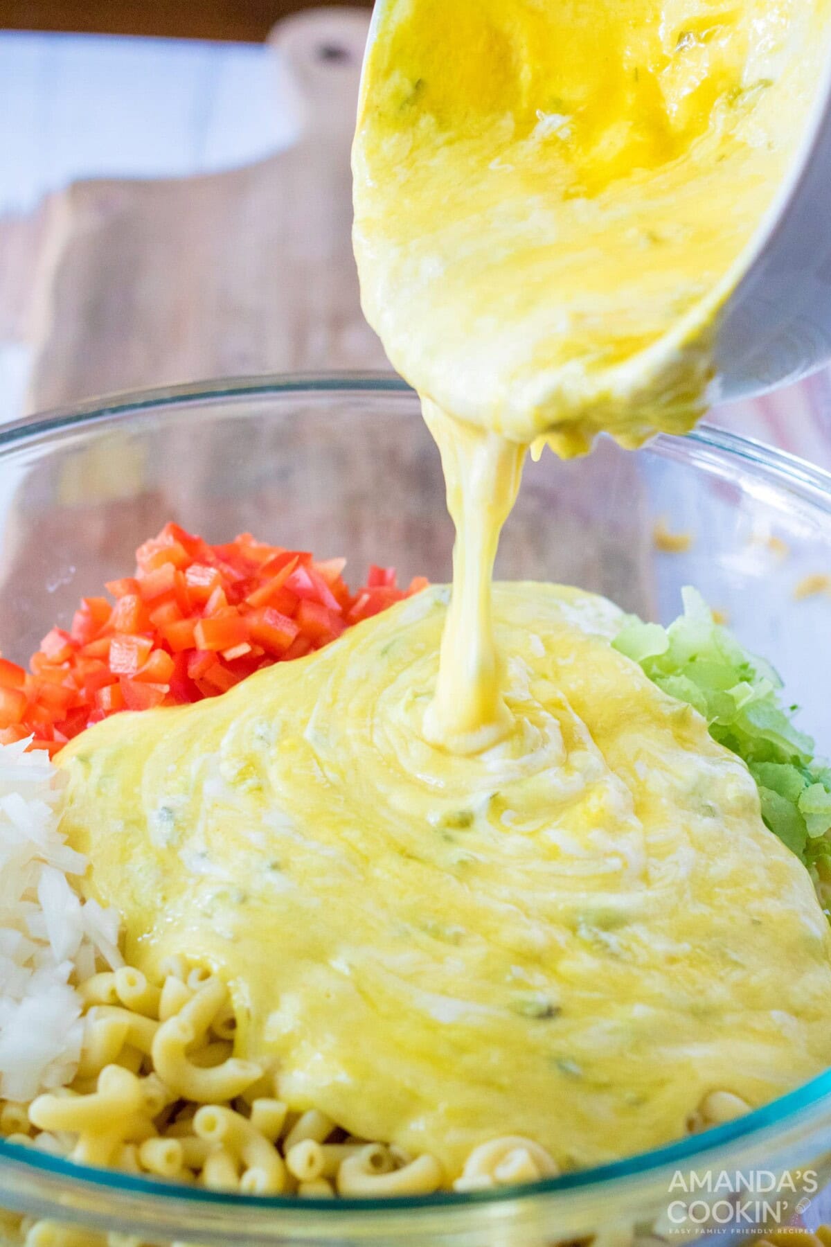 pouring dressing over macaroni and vegetables