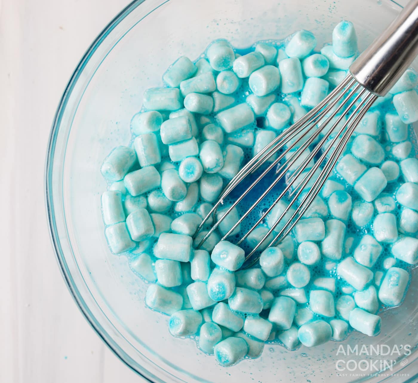 blue jello with marshmallows in a bowl with whisk