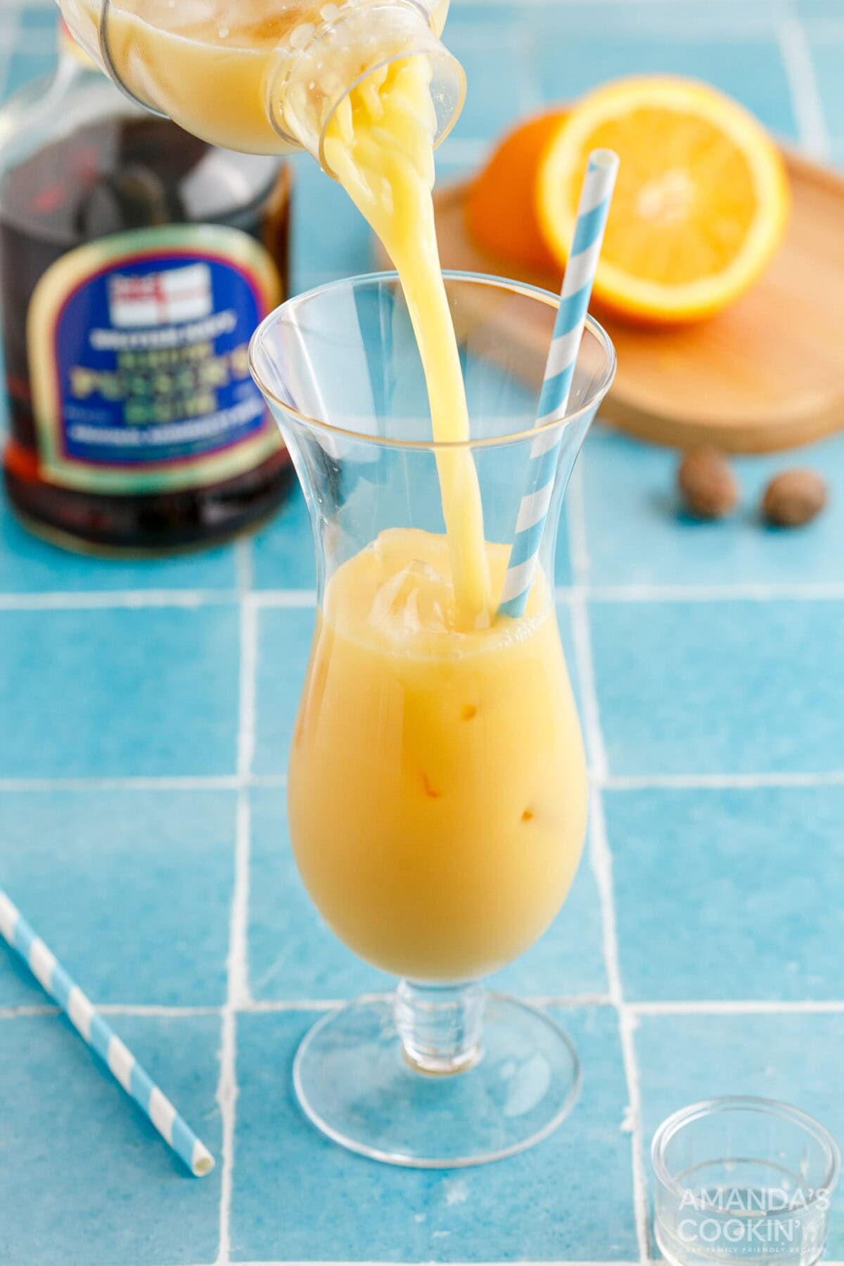 pouring painkiller cocktail into hurricane glass