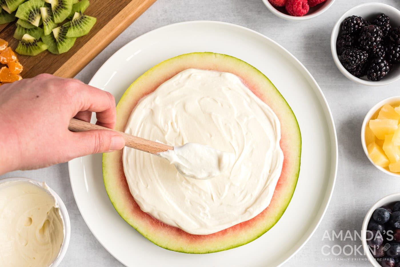 rubber spatula spreading cream cheese and yogurt mixture over watermelon slice