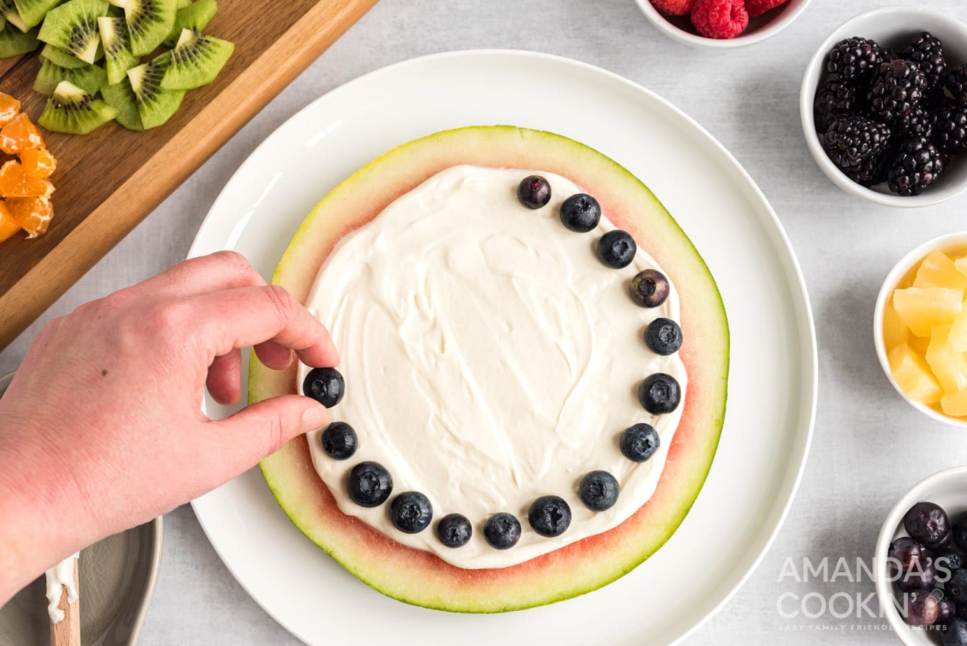 hand placing blueberries around watermelon slice