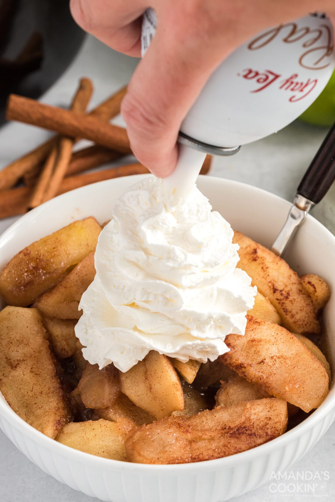 adding whipped cream to Crockpot Cinnamon Apples