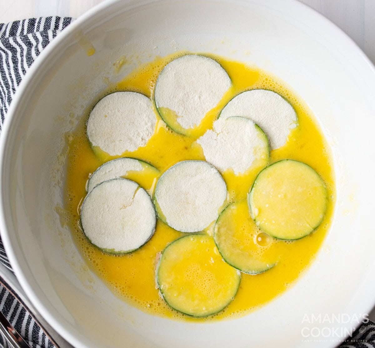 dredging flour coating zucchini slices in egg