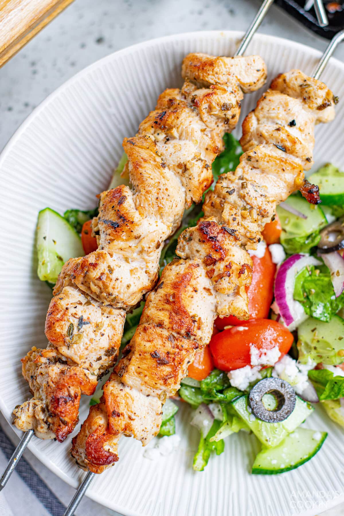 Greek Chicken Kabobs on a plate with salad