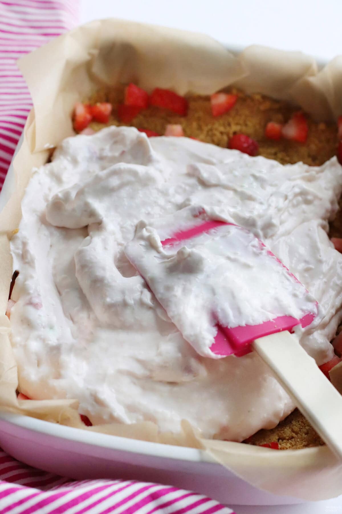 spreading cream cheese cheesecake layer on top of graham cracker crust