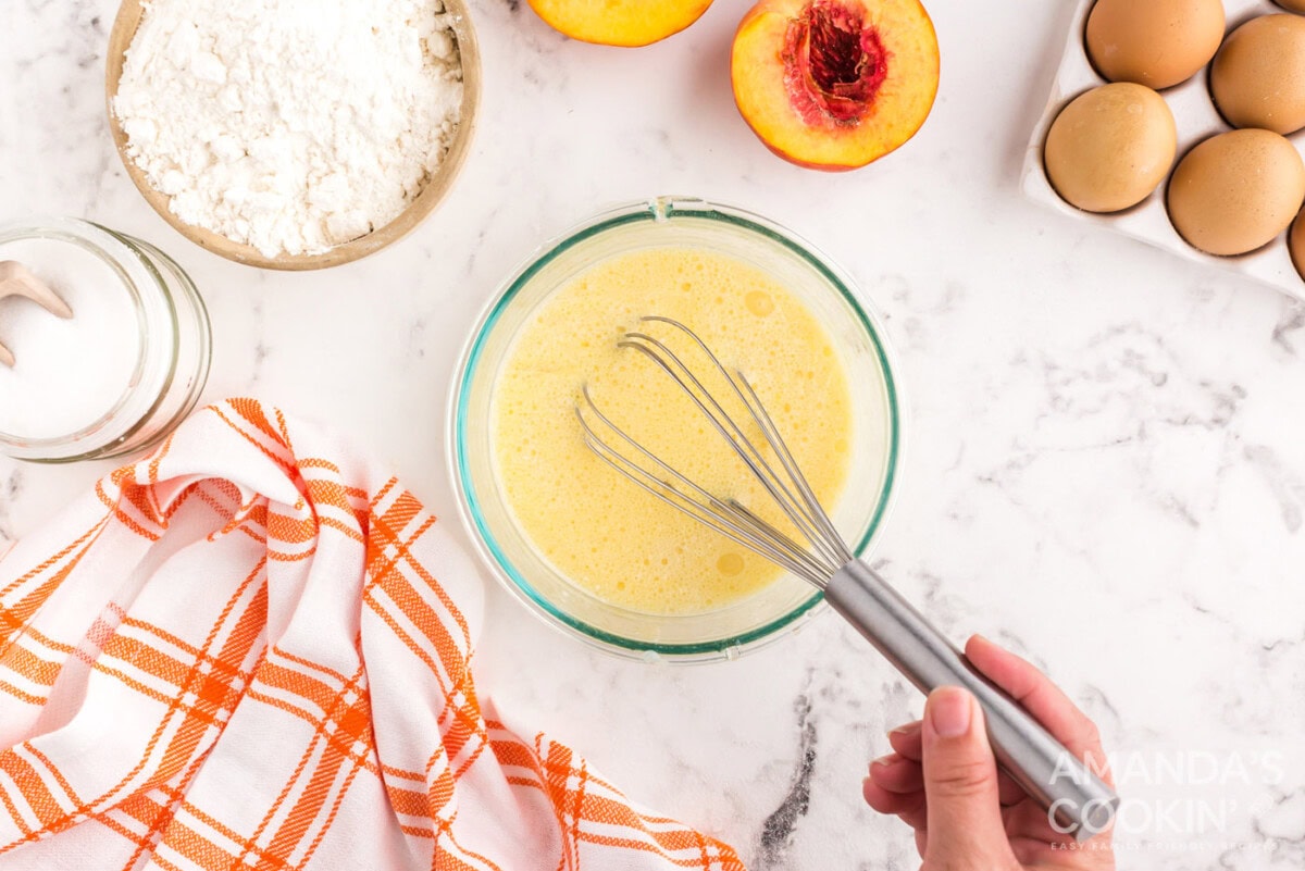 whisking milk, eggs, oil, vanilla, and almond extracts