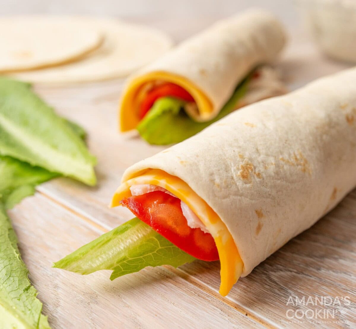 rolled tortillas with tomato, lettuce, meat, and cheese