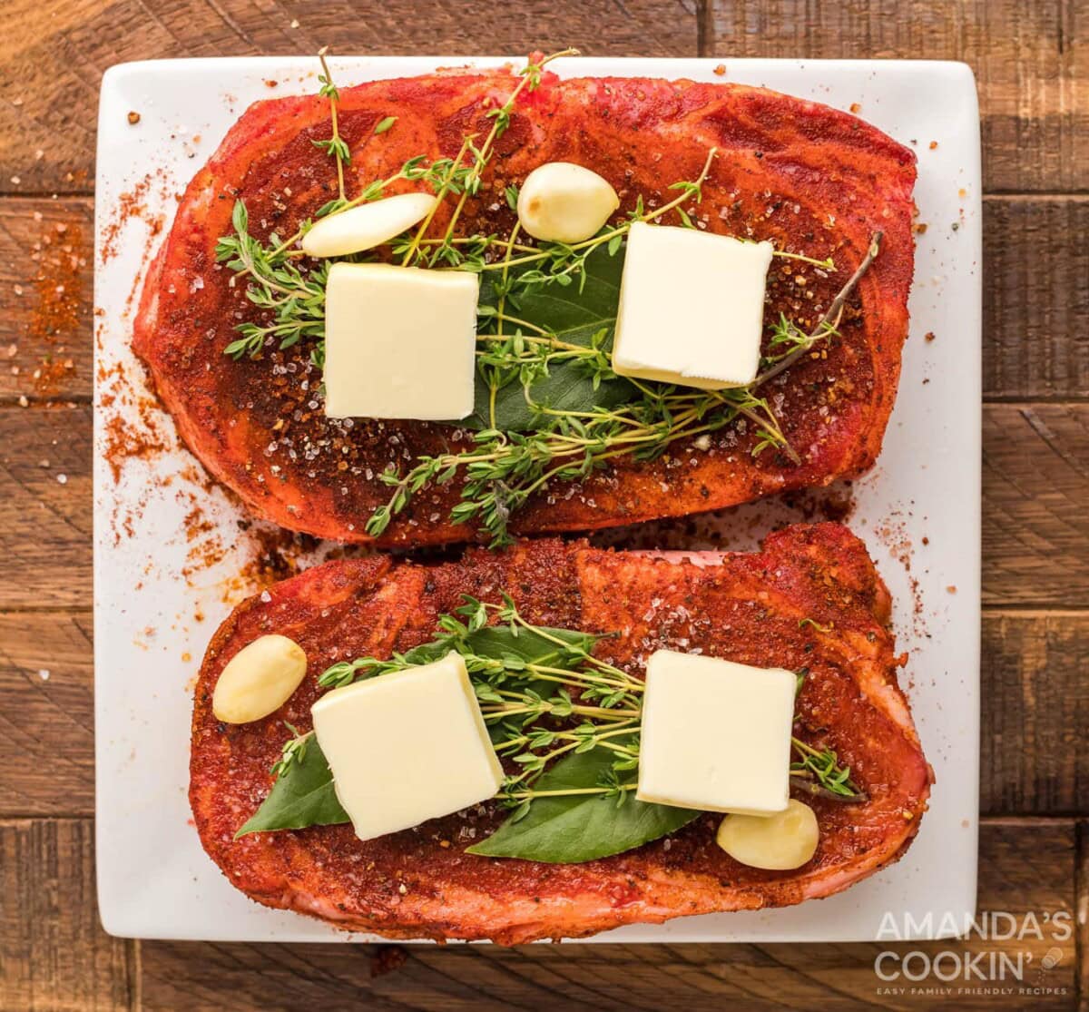 ribeye meat with butter pats, bayleaf, and rosemary sprigs