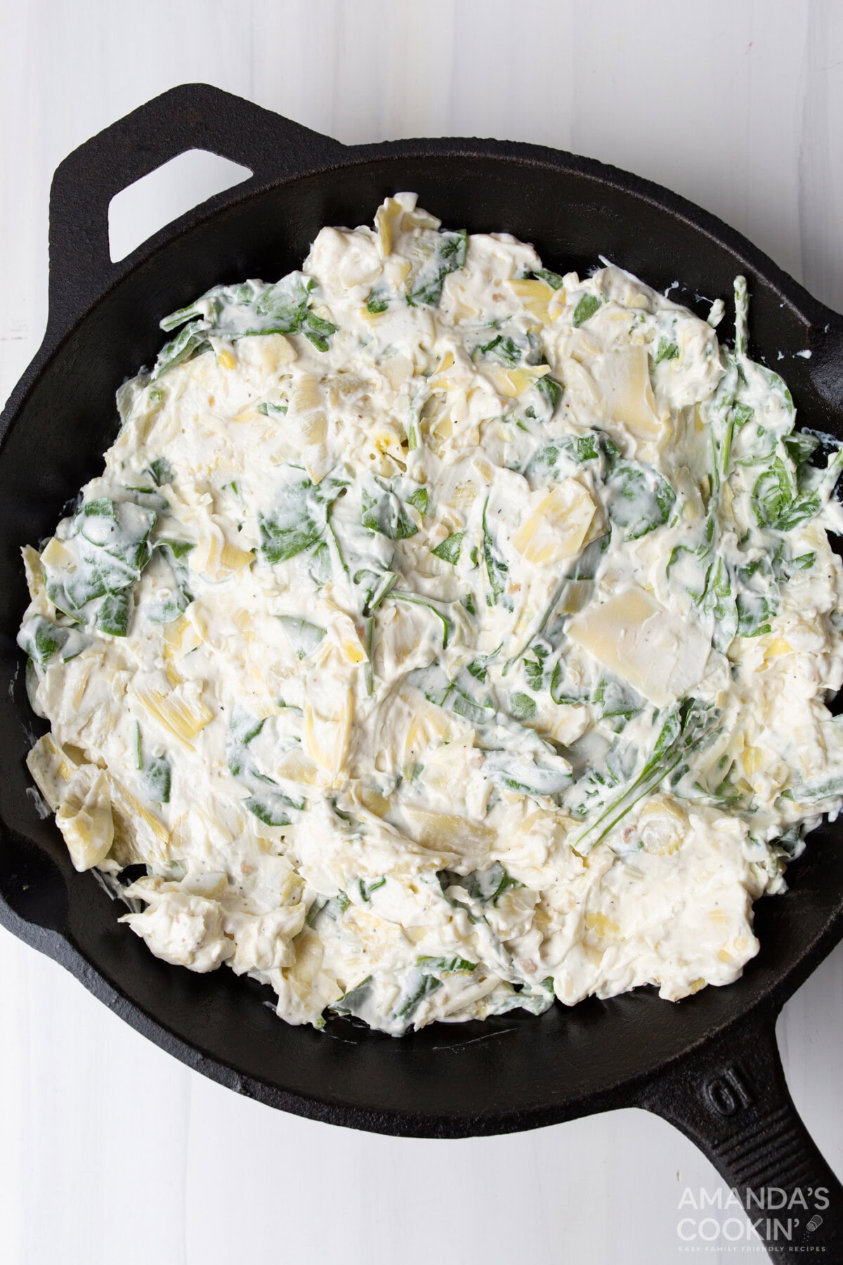 Spinach artichoke dip ingredients in a skillet