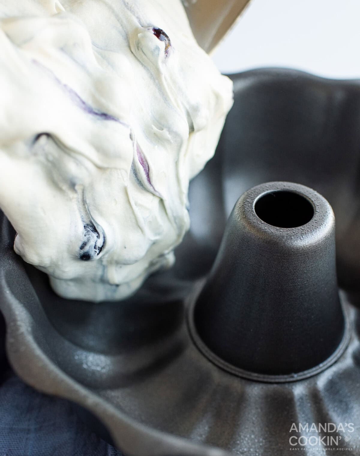 pouring blueberry cake batter into bundt pan