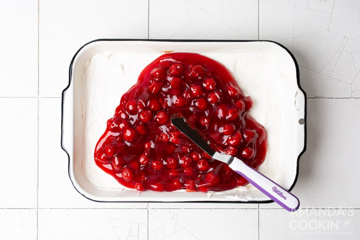 cherry pie filling on top of cream cheese mixture in baking pan