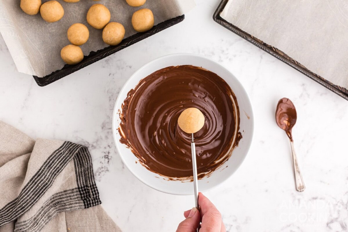 Dipping peanut butter ball into melted chocolate