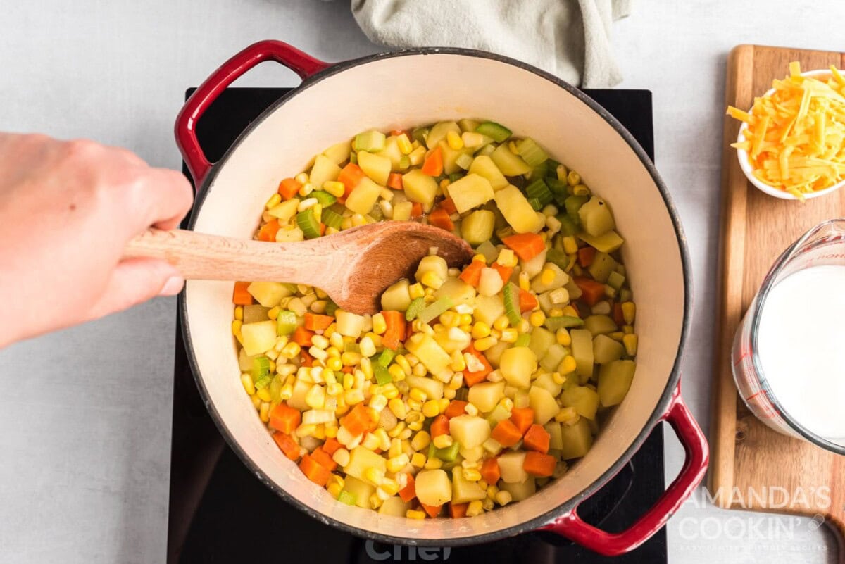 Corn being mixed into the veggie mixture in a pot