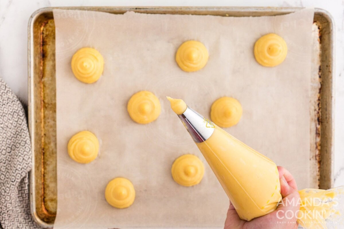 piping choux pastry dough onto baking sheet