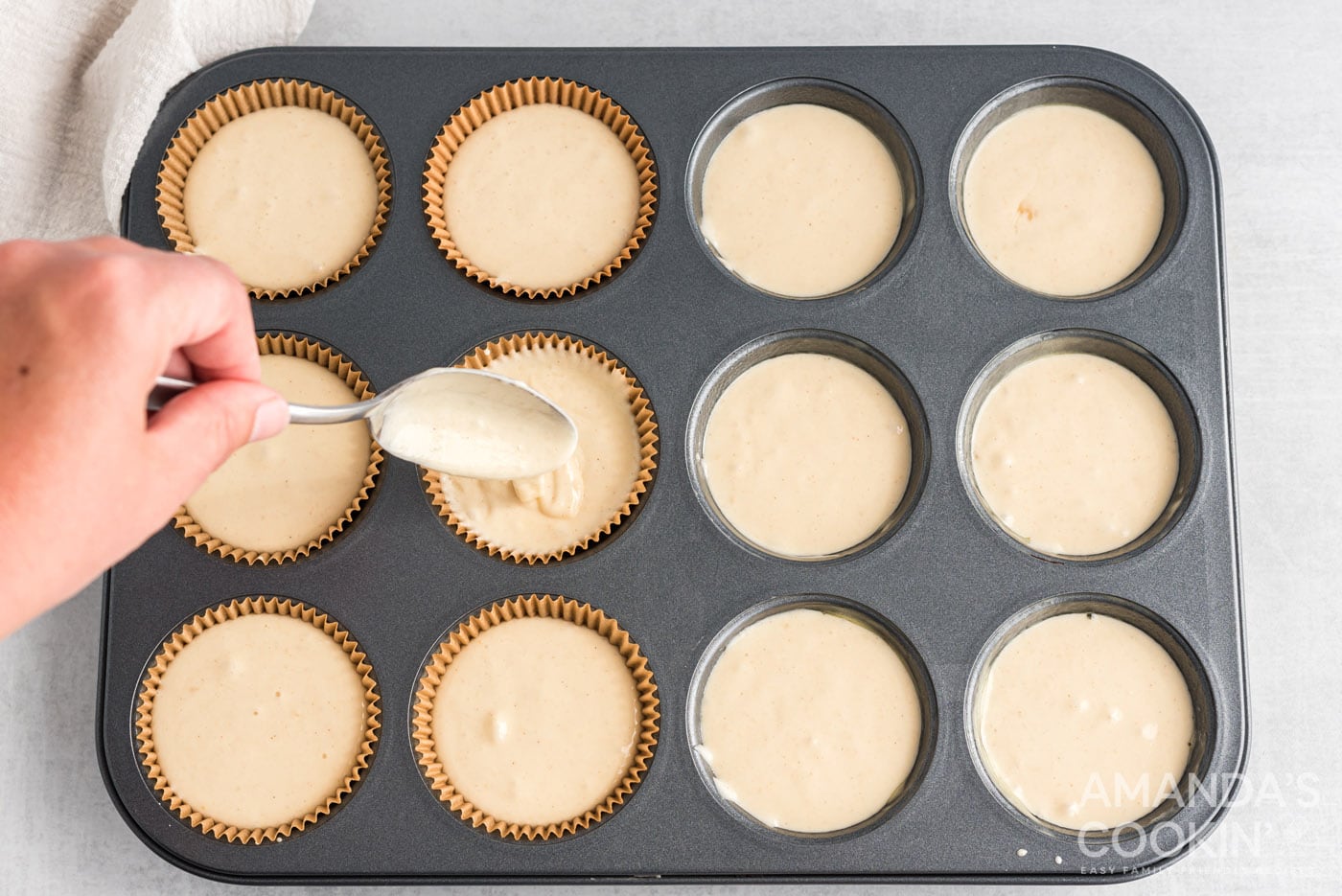 spoon scooping cupcake batter into baking pan