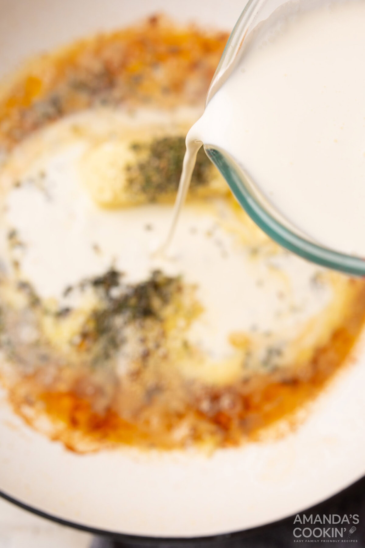 pouring heavy cream into skillet for alfredo sauce