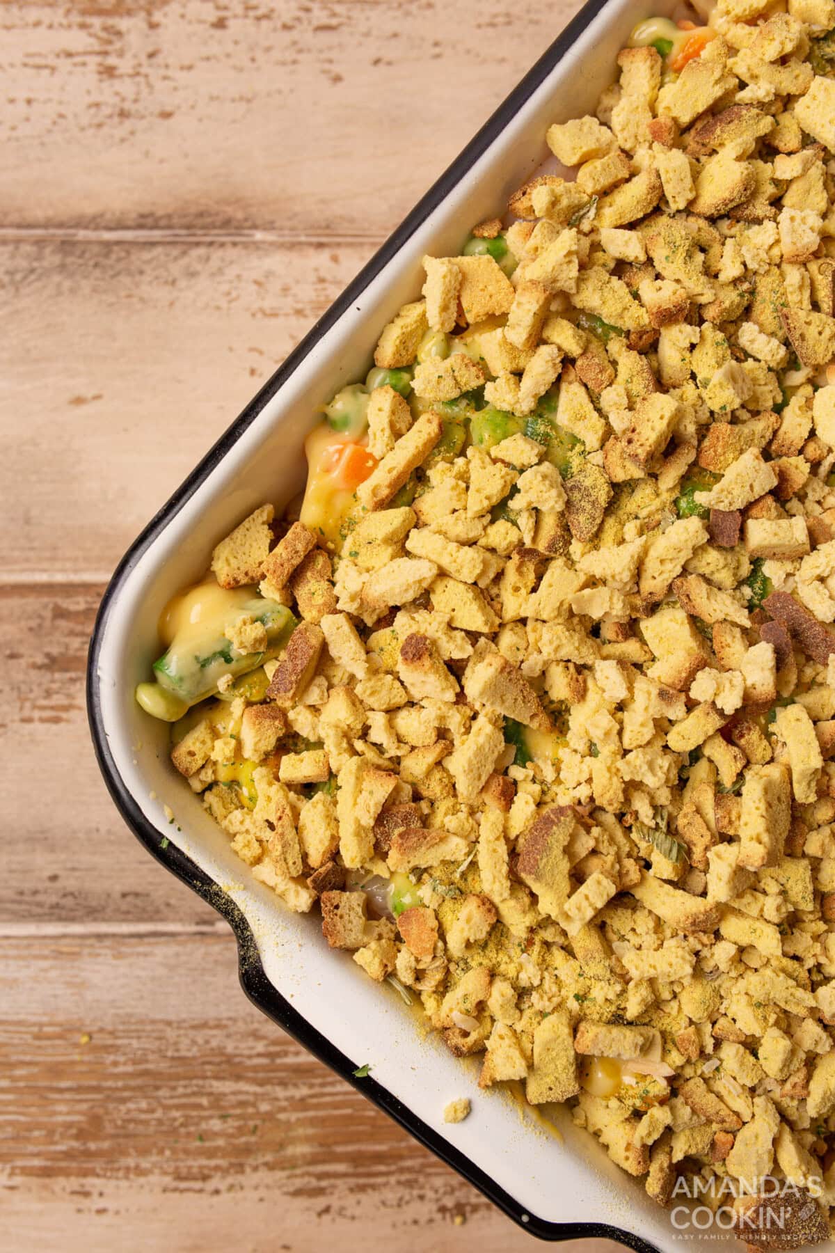 dried bread cubes on top of veggies and chicken in a casserole dish
