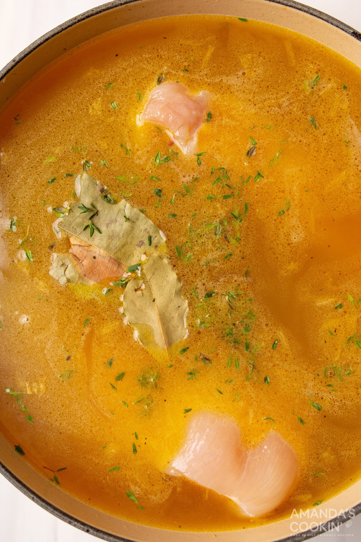 bay leaves, thyme, and chicken breasts in chicken noodle soup broth