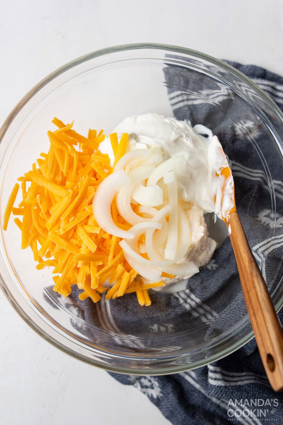 sour cream, mayo, cheese, and onions mixed in a bowl
