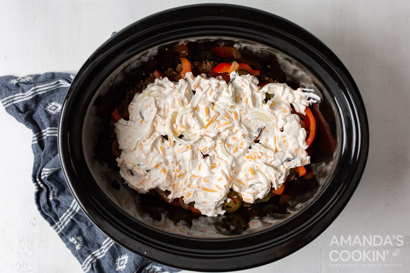 sour cream mixture on top of ground beef and veggies in slow cooker