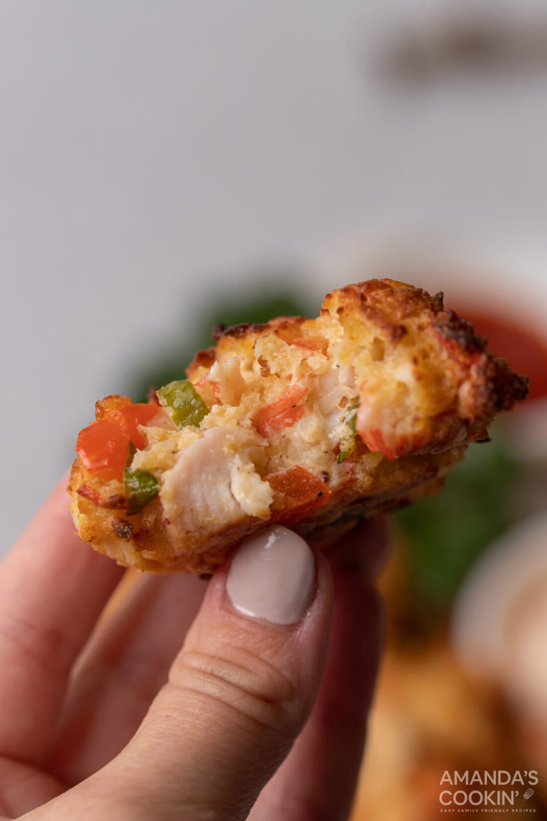 holding an Air Fryer Crab Cake with a bite out of it