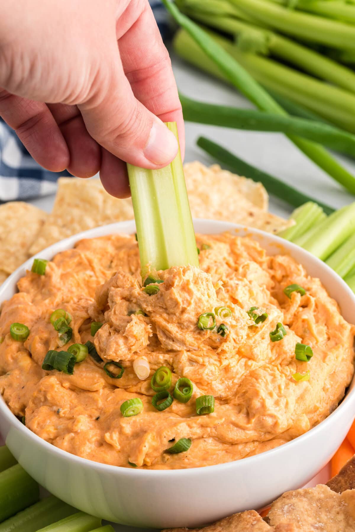 dipping celery stick into Buffalo Chicken Dip