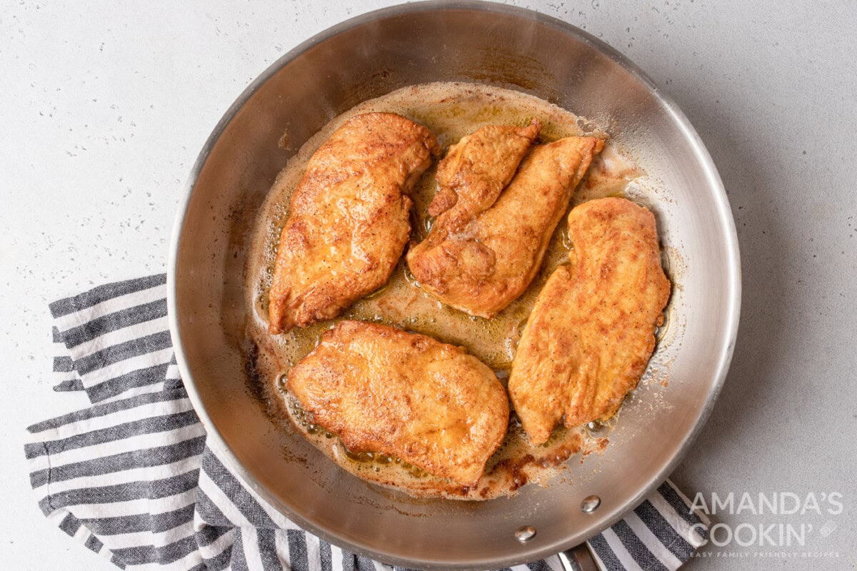 chicken cooking on a pan with butter and oil