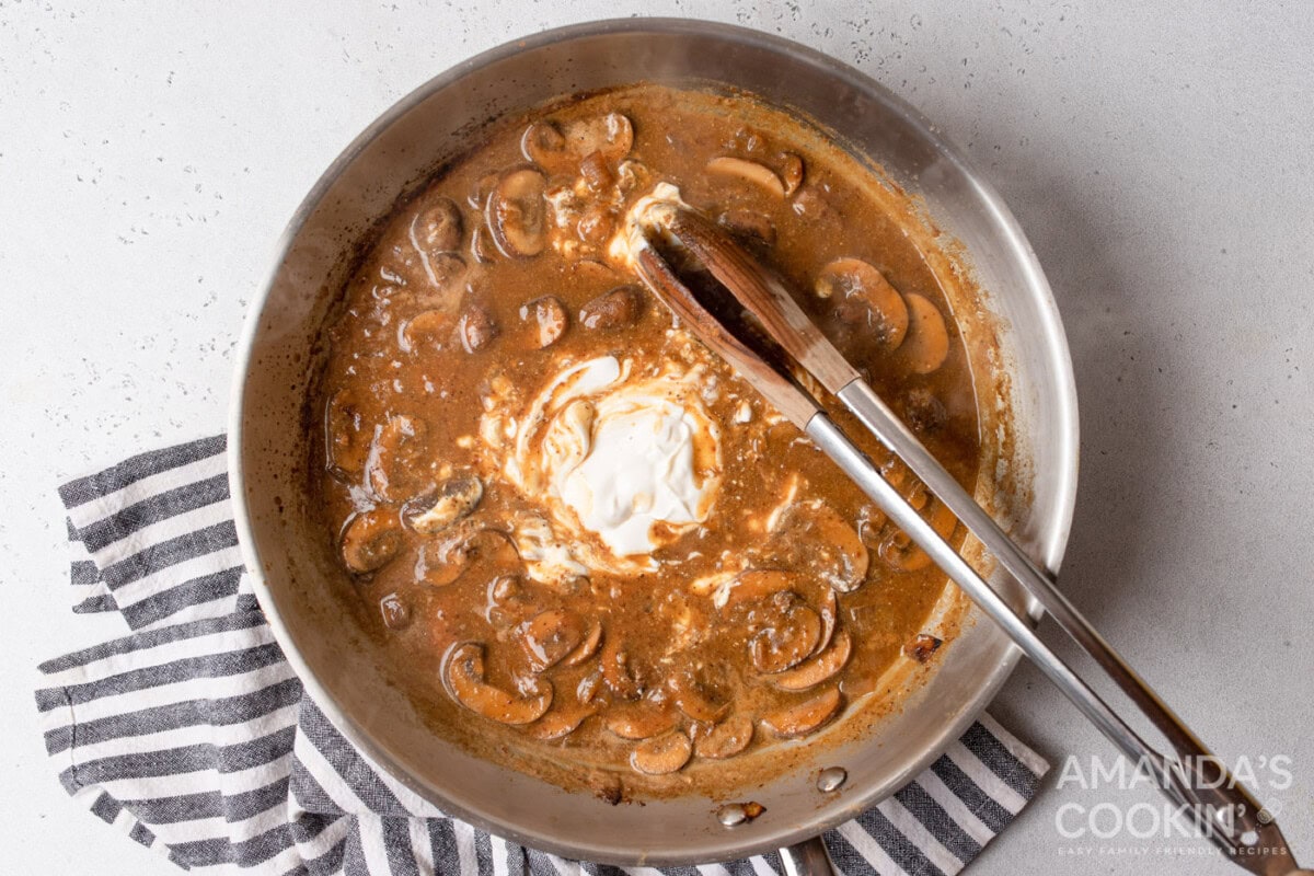 stirring sour cream into stroganoff sauce