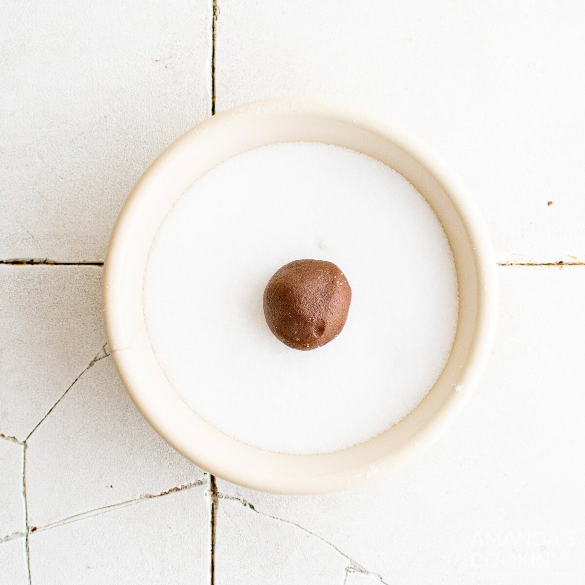 chocolate cookie dough ball in a bowl of sugar
