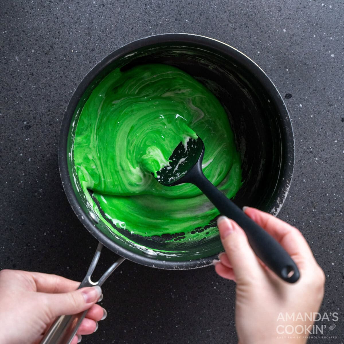 spoon stirring green food coloring into melted marshmallows