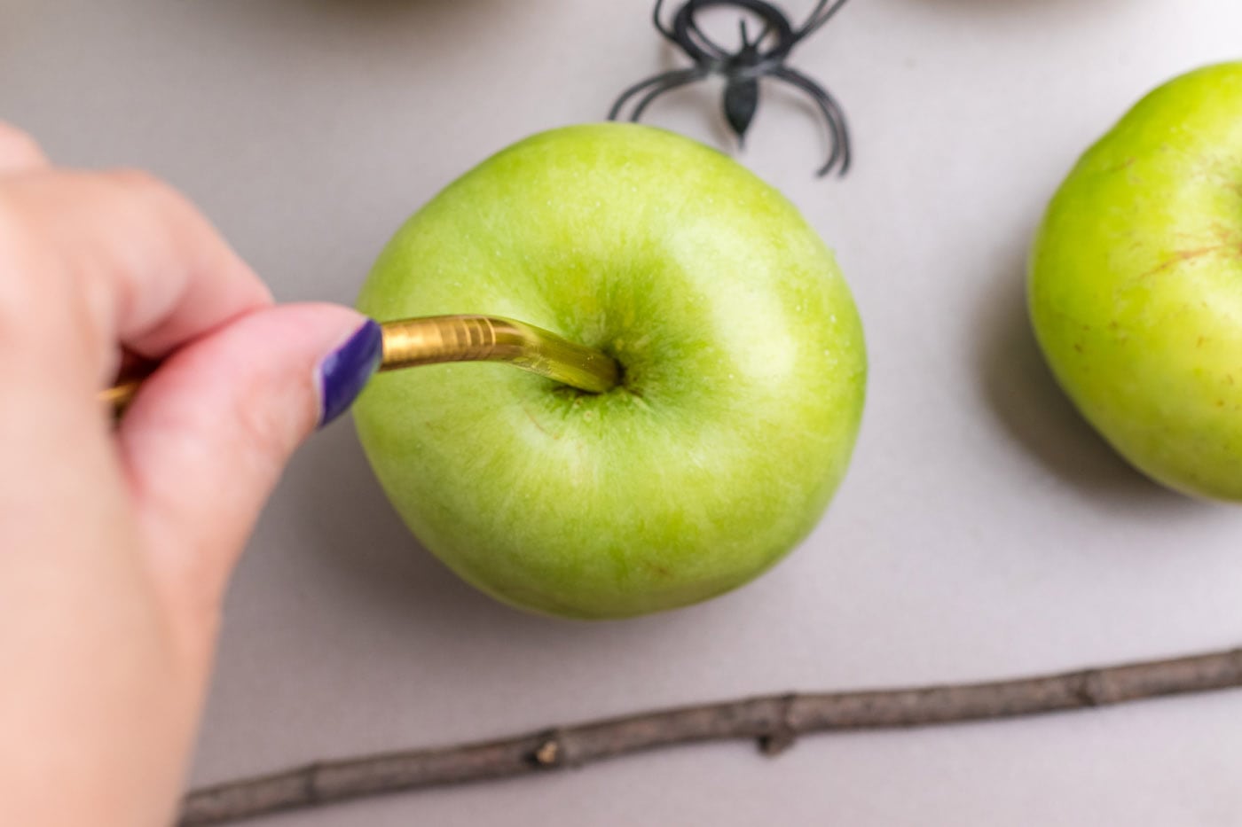 sticking a metal straw into green apple
