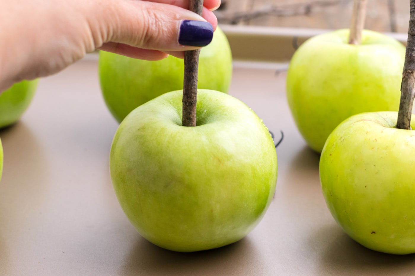 hand placing a stick into a green apple