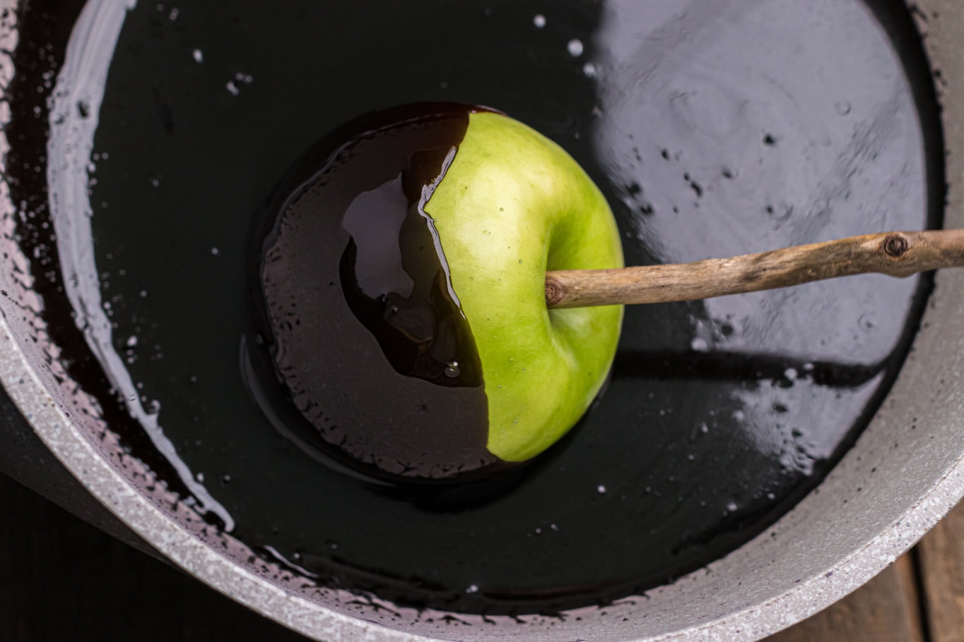 dipping apple into black candy coating
