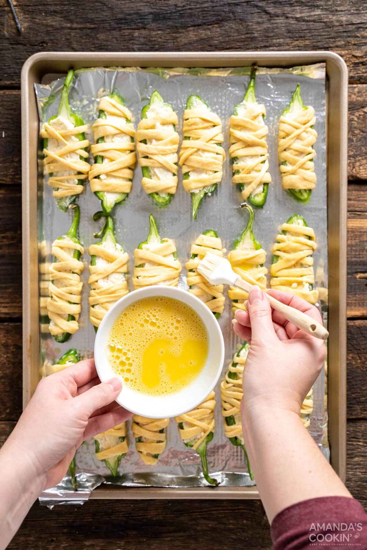 brushing egg wash on jalapeno poppers