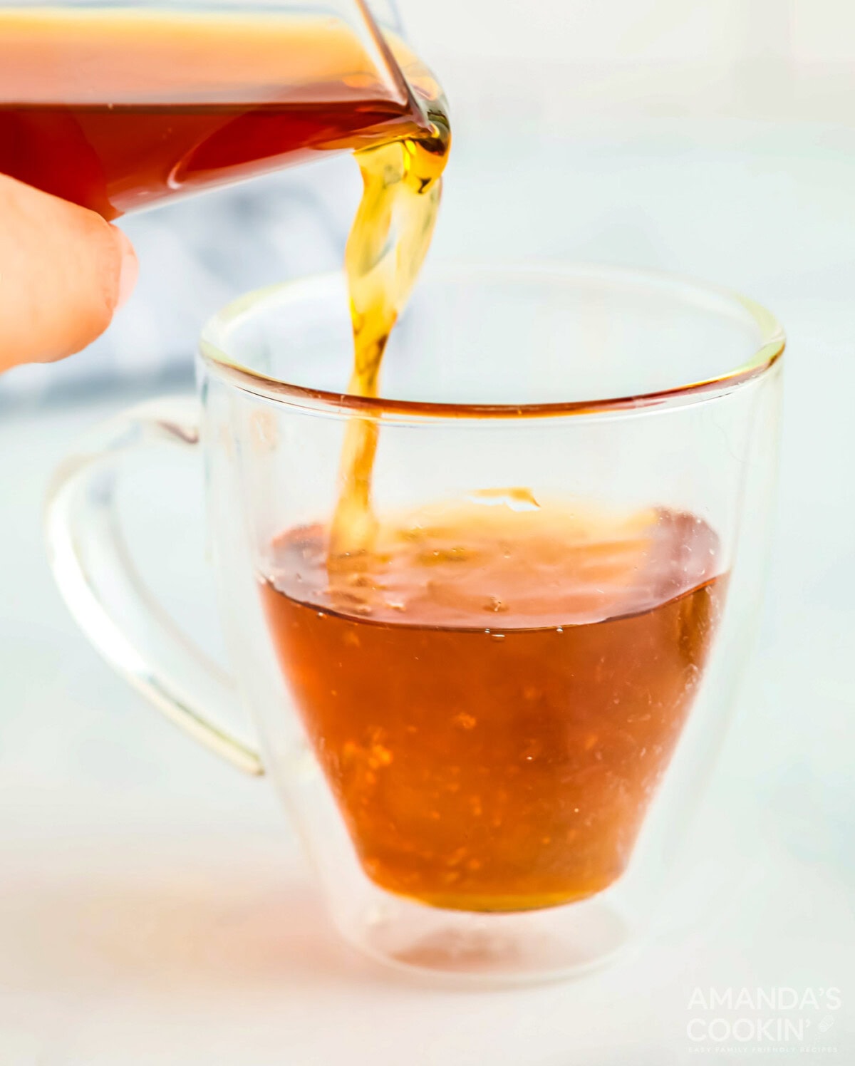 pouring apple cider into a glass mug with whiskey and vodka