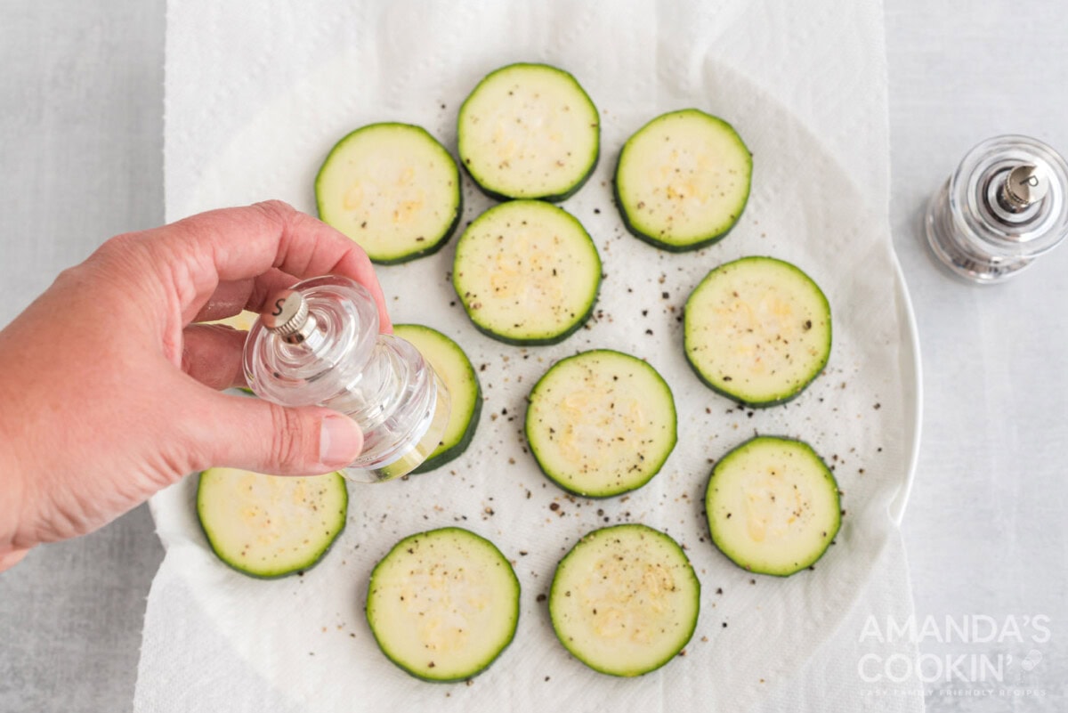 seasoning zucchini rounds with salt and pepper