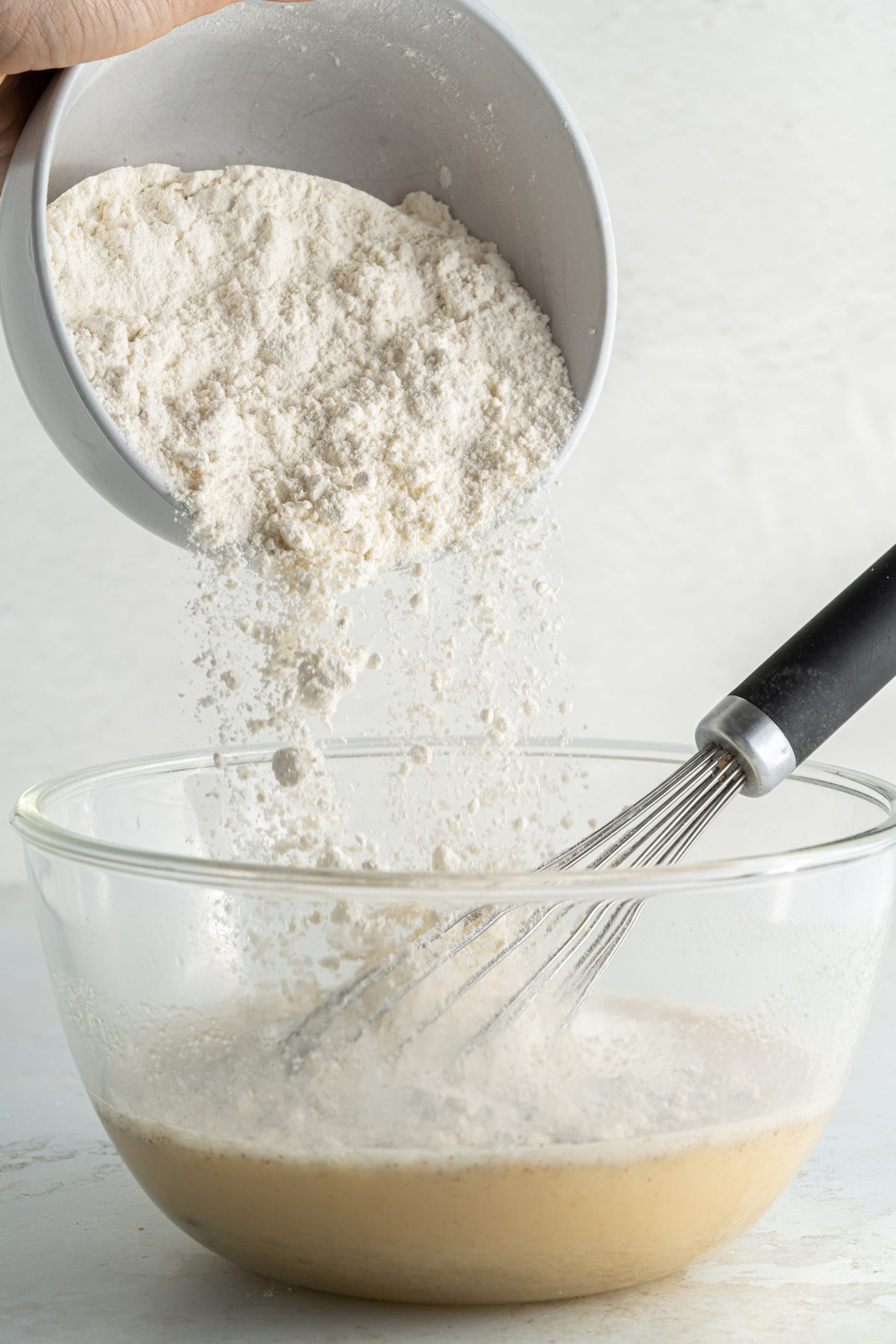 adding flour to pancake batter in a bowl