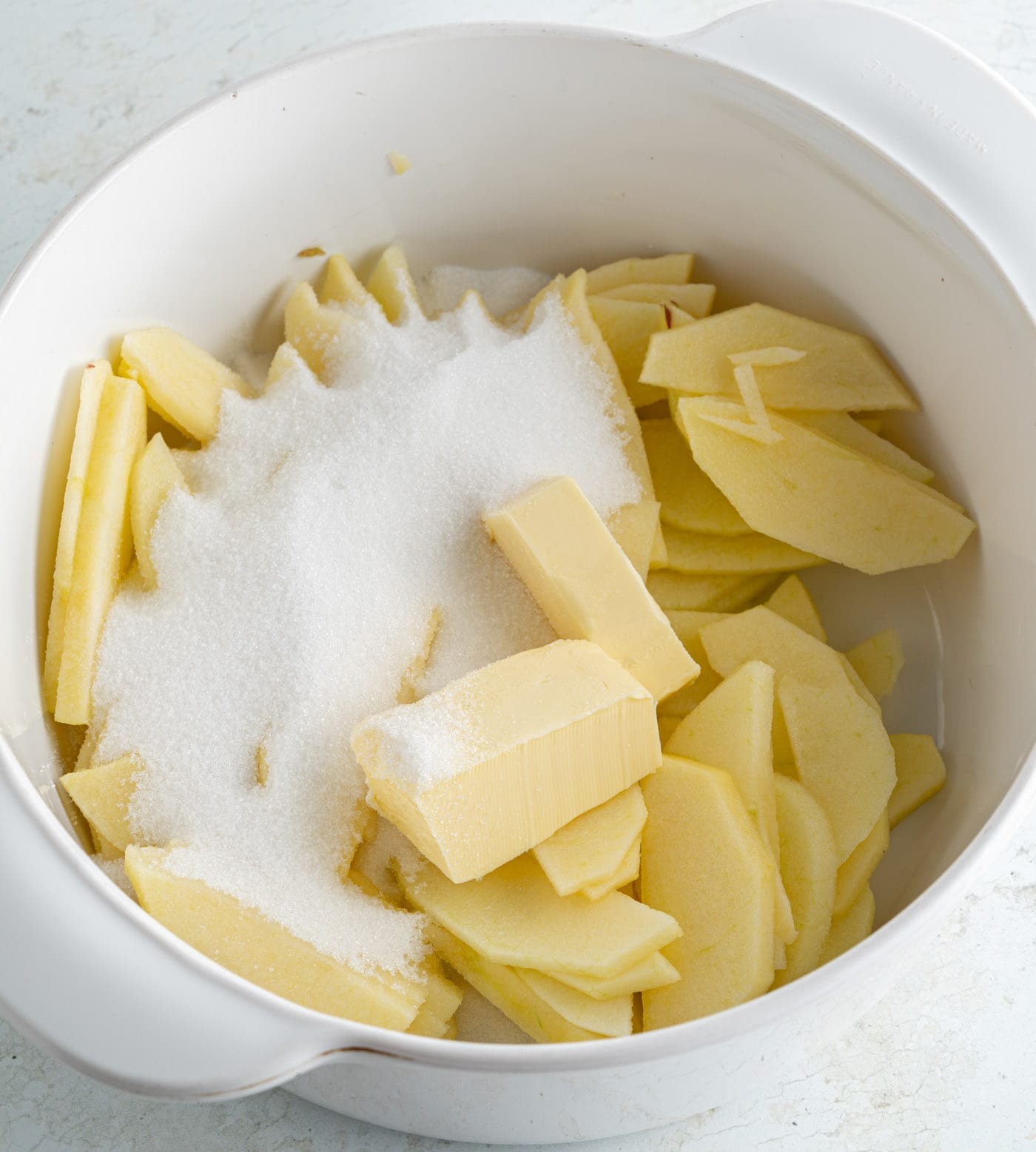 sugar and butter in a bowl with sliced apples