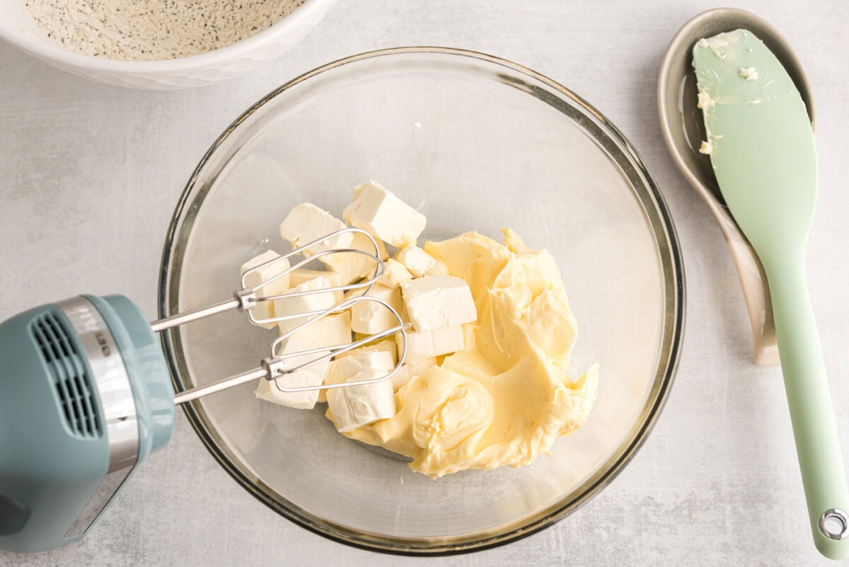 butter and cream cheese in a bowl with a handheld mixer