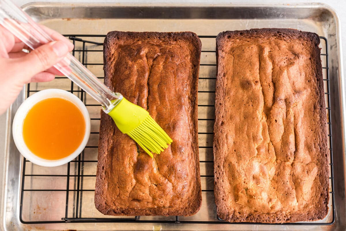brushing orange pound cake with glaze